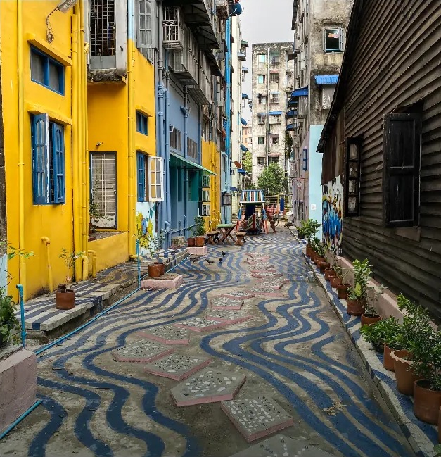 A Yangon back alley painted with blue and white waves, lined with plants and benches